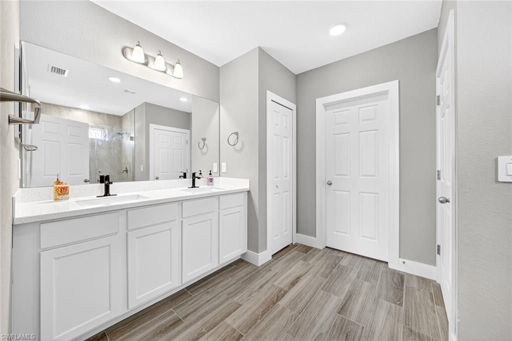 Full bath featuring a shower stall, double vanity, wood tiled floors, recessed lighting, and a closet