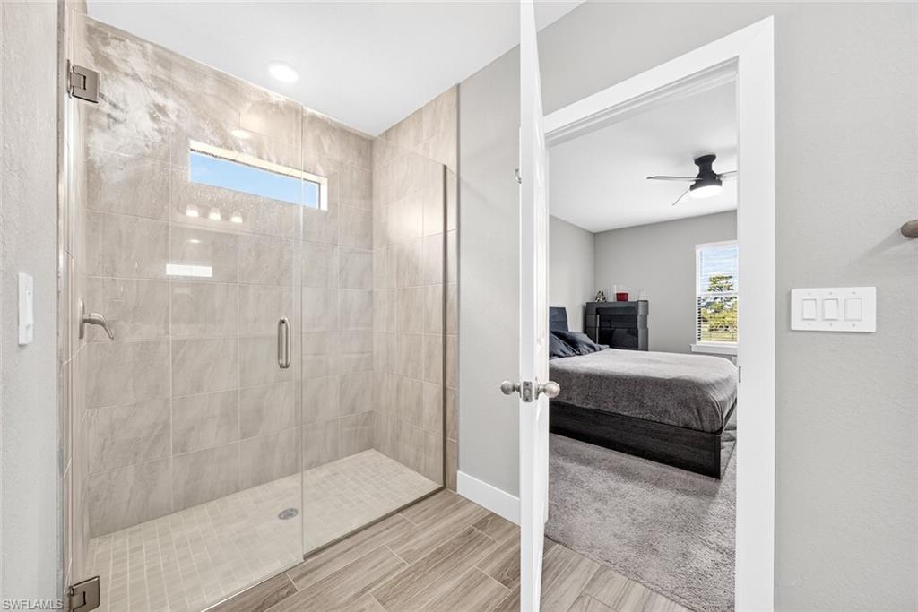 Full bath featuring healthy amount of natural light, a stall shower, ensuite bath, and a ceiling fan