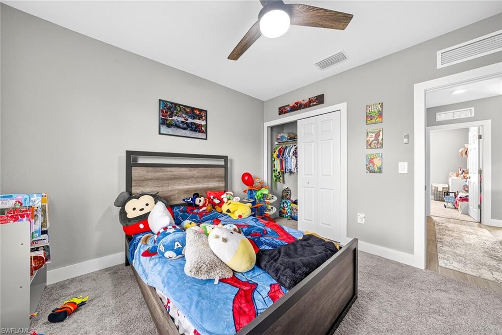 Bedroom with light carpet, a closet, and ceiling fan