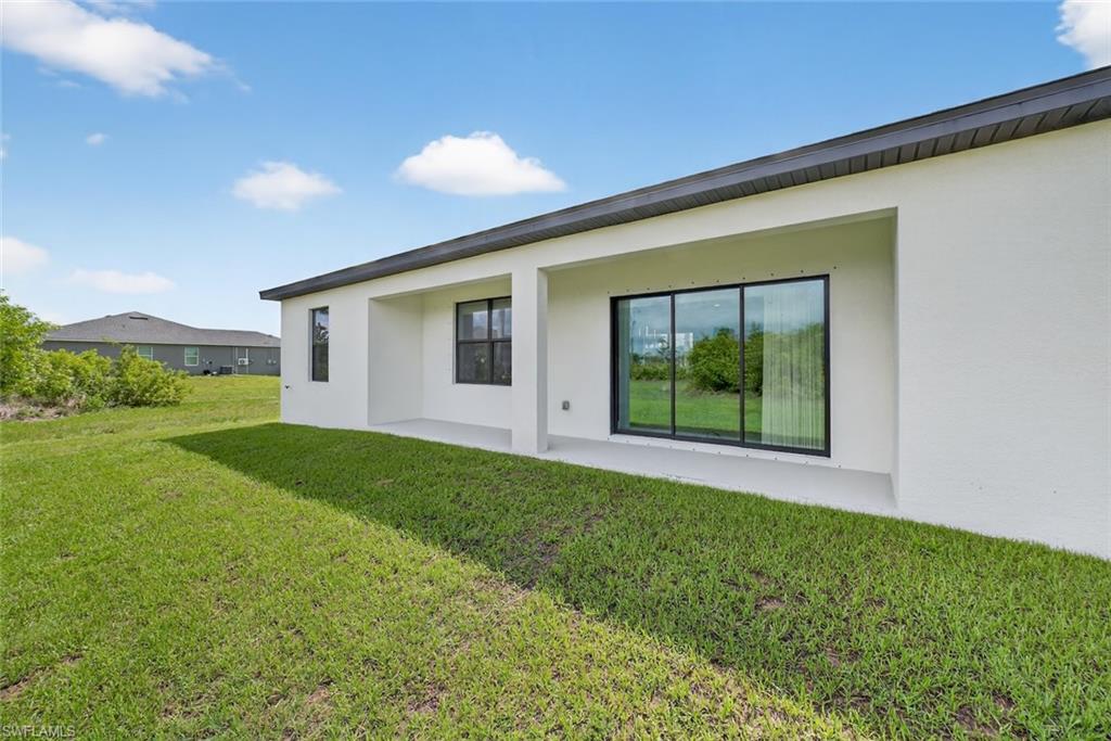 Rear view of property with stucco siding, a yard, and a patio area