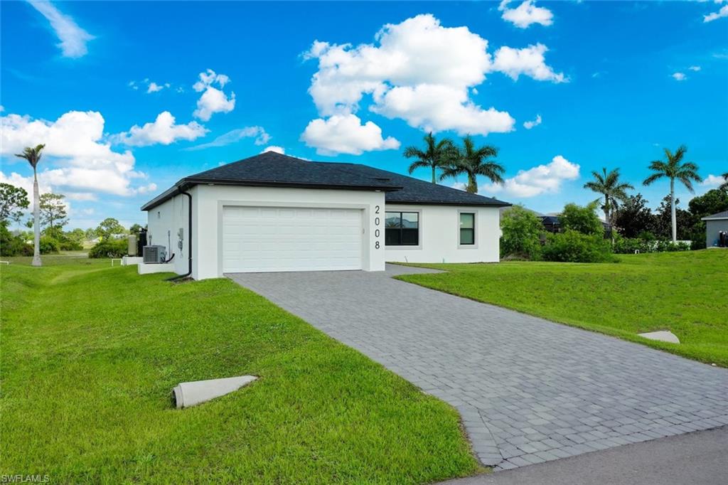 View of property exterior featuring a yard, stucco siding, decorative driveway, and an attached garage