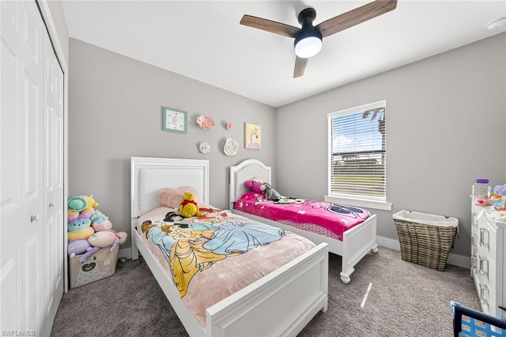 Carpeted bedroom with ceiling fan and a closet