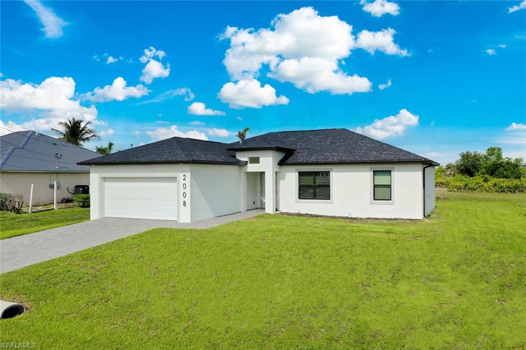 View of front of house with a front lawn, stucco siding, decorative driveway, a garage, and roof with shingles