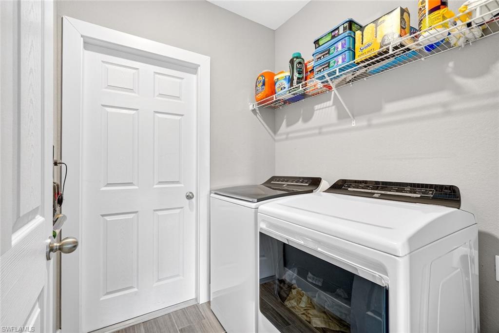 Laundry room with washer and clothes dryer and light wood-style floors