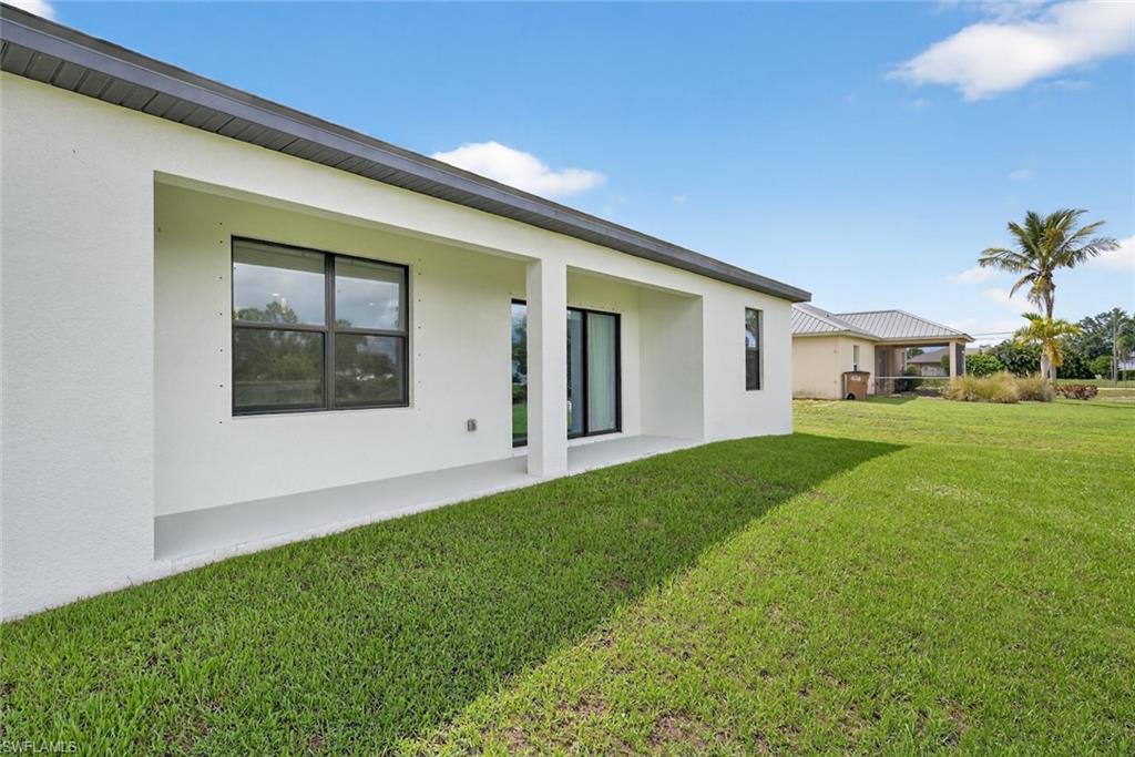 Rear view of property with stucco siding, a yard, and a patio