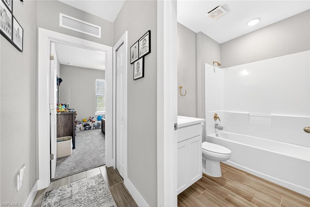 Bathroom with vanity, wood finish floors, and bathtub / shower combination