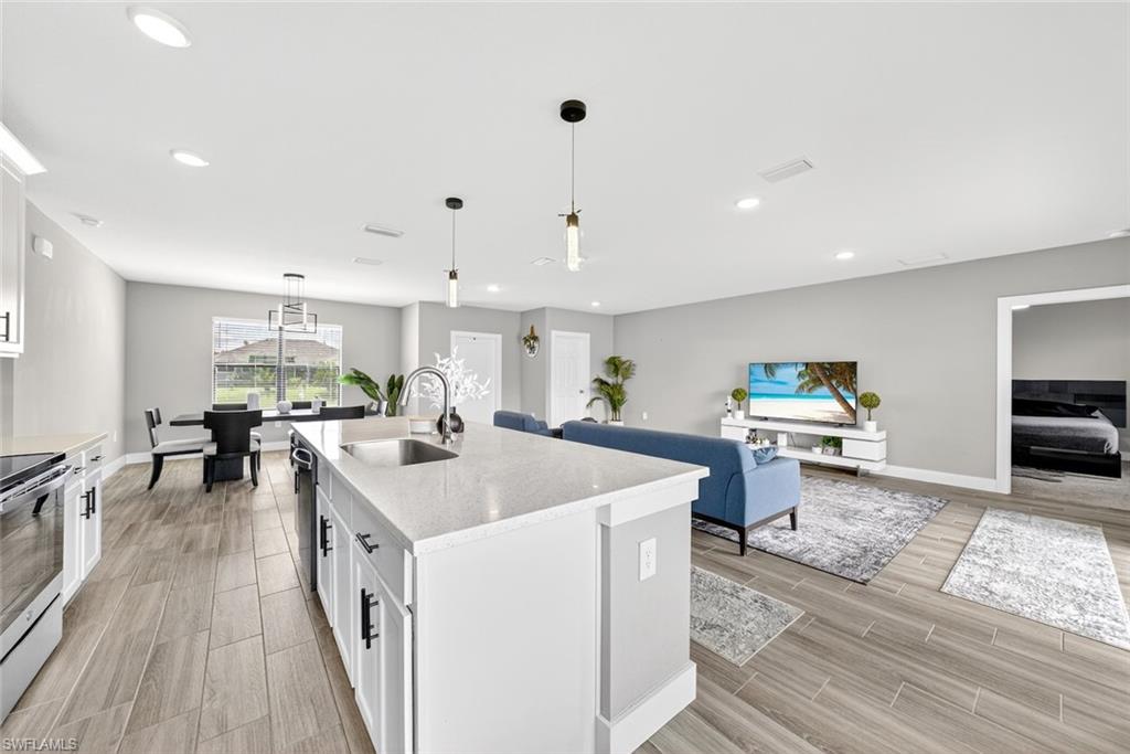 Kitchen with white cabinets, decorative light fixtures, wood finish floors, and recessed lighting