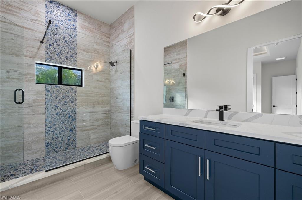 Bathroom with hardwood / wood-style floors, vanity, toilet, and a shower with shower door