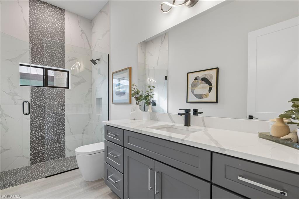 Bathroom featuring hardwood / wood-style floors, vanity, a shower with shower door, and toilet
