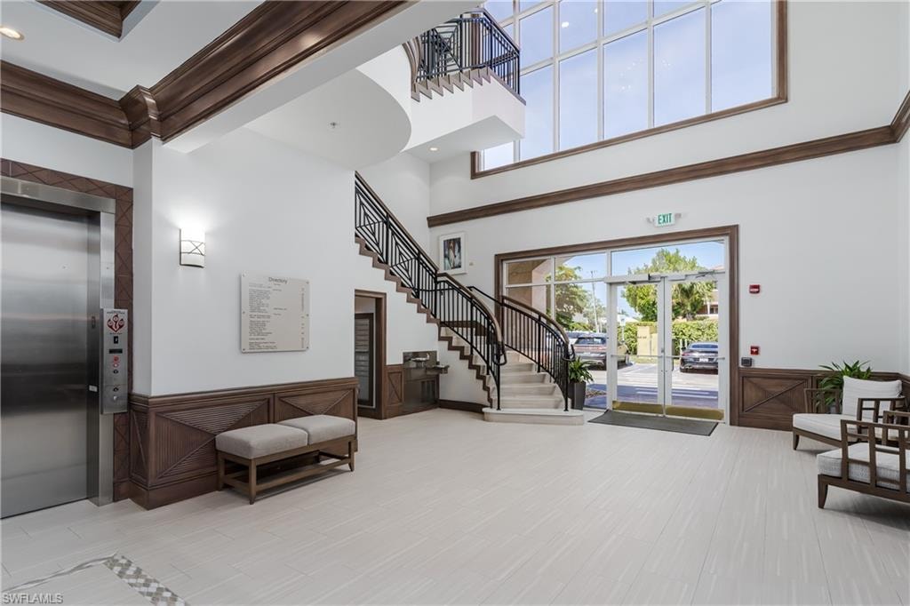 Two-story foyer featuring an elevator, a grand staircase with wrought iron railings, and extensive natural light through large windows