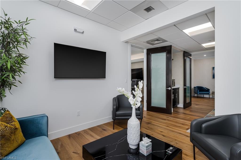 Reception area featuring wood-finish flooring, white walls, and a drop ceiling with integrated lighting