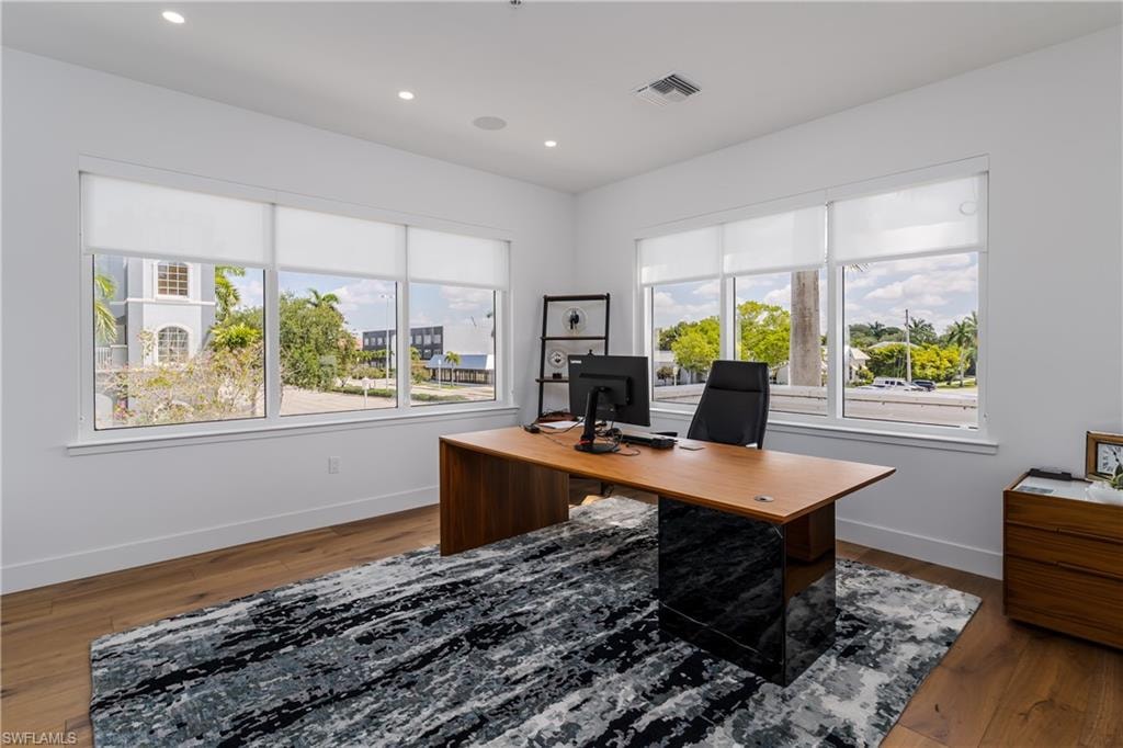 Dedicated workspace featuring wood-finish flooring, recessed lighting, and expansive windows with roller shades