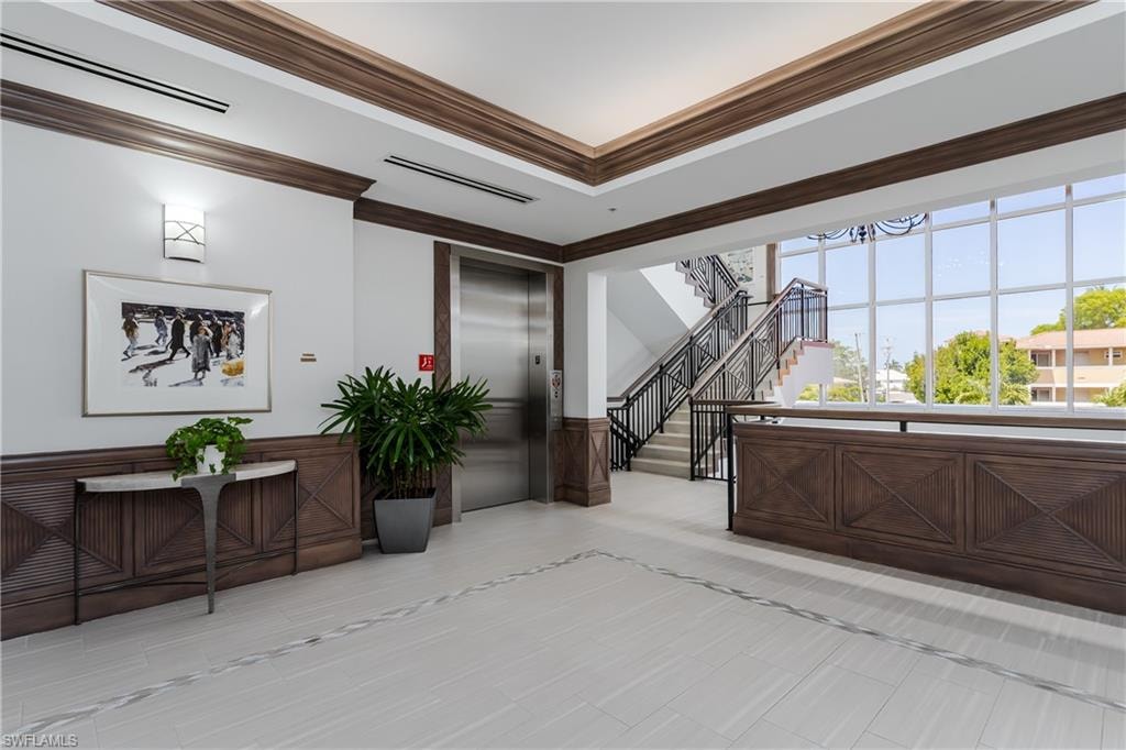 Lobby area featuring light tile flooring with decorative inlay, extensive dark wood paneling, and a full-height window wall