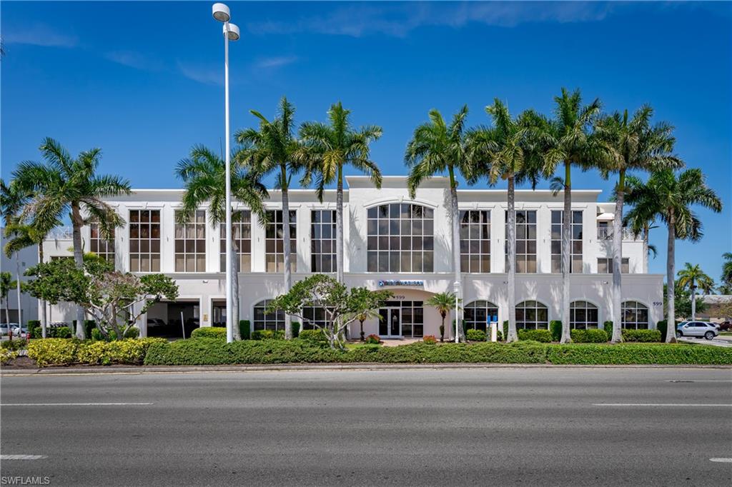 Multi-story commercial building featuring a white stucco facade with arched windows on the ground level