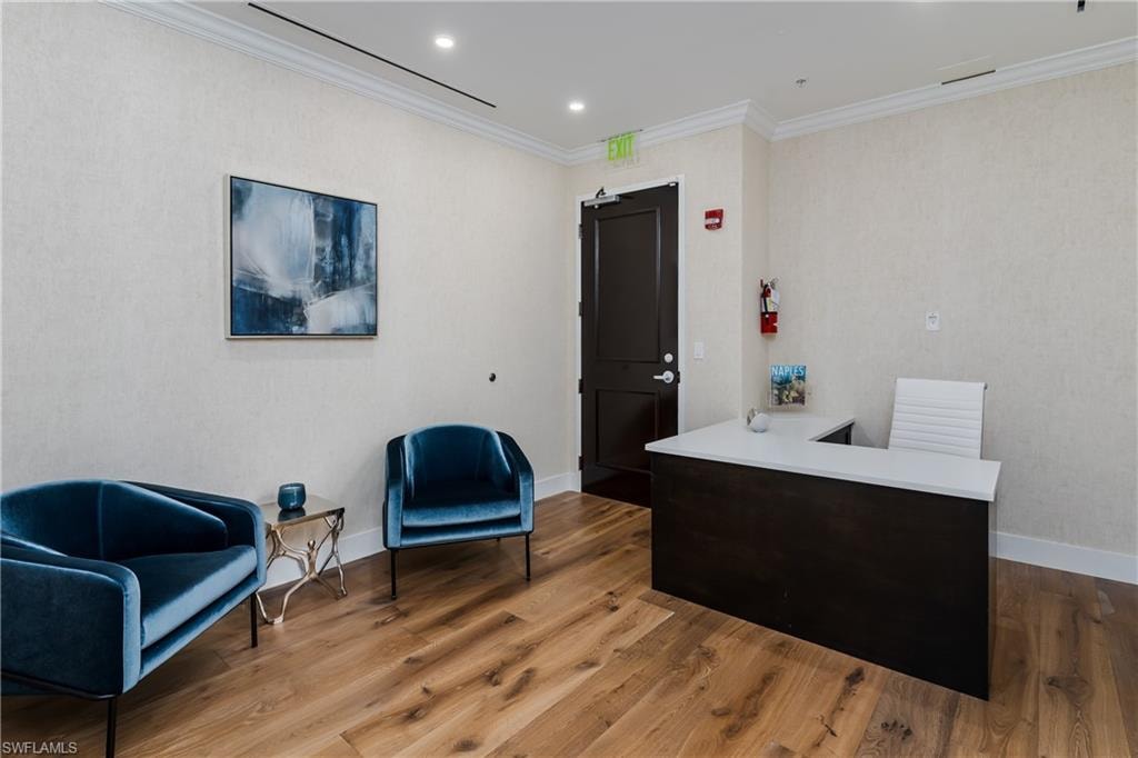 Spacious reception area featuring wood-finish flooring, textured wall coverings, and white crown molding