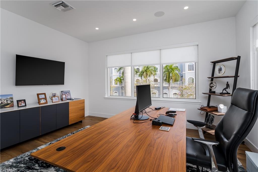 Dedicated office space featuring wood-finish flooring, recessed lighting, and a window with roller shades