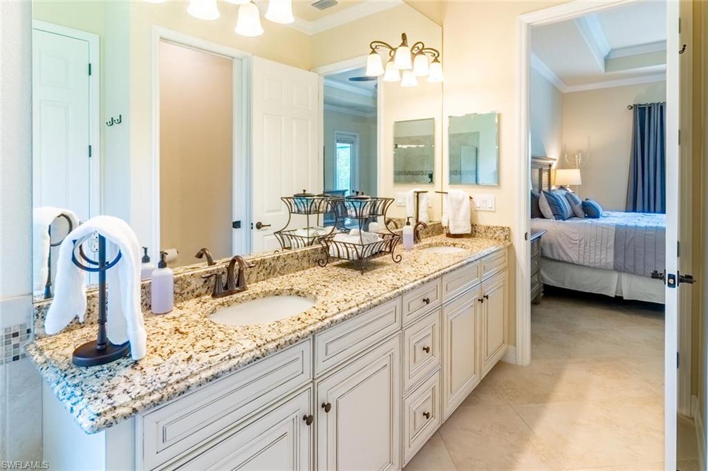 Bathroom with crown molding, a raised ceiling, dual vanity, and tile patterned flooring