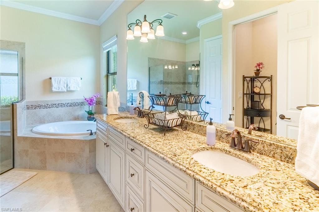 Bathroom featuring tile patterned floors, a wealth of natural light, double sink vanity, and a relaxing tiled tub