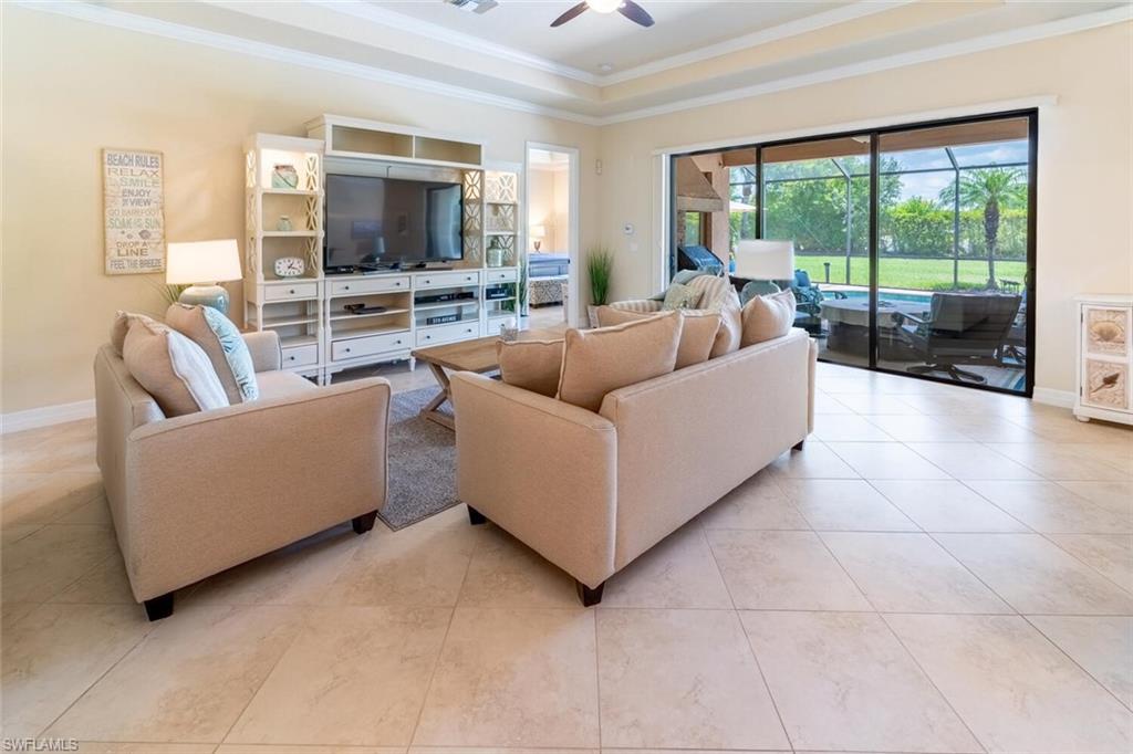 Living room featuring ceiling fan, light tile patterned flooring, and a raised ceiling