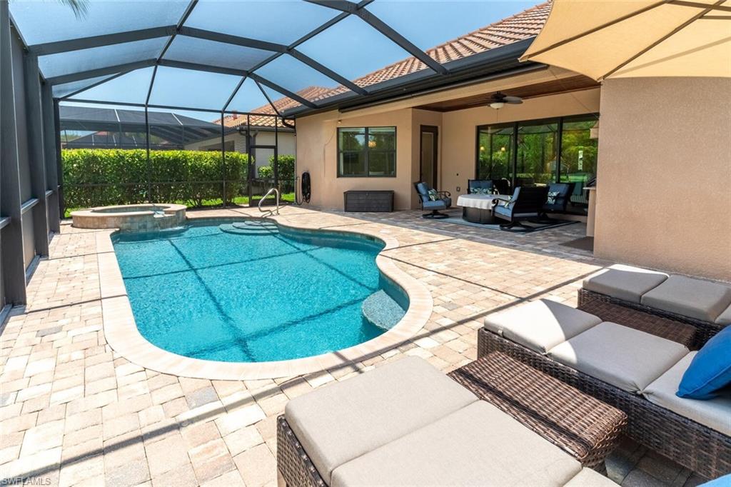 View of pool with ceiling fan, an in ground hot tub, glass enclosure, a patio area, and outdoor lounge area