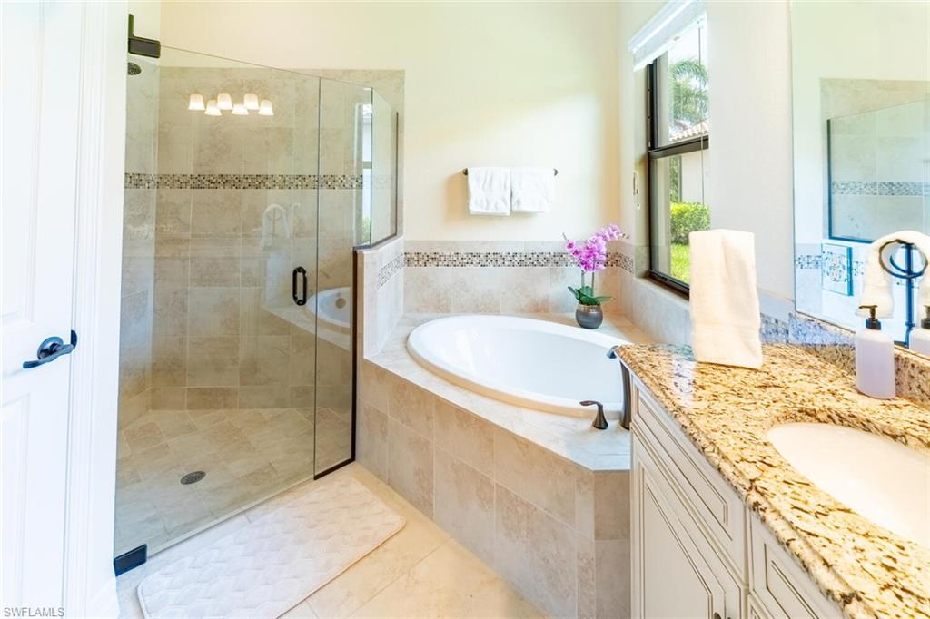 Bathroom featuring tile patterned floors, vanity, and separate shower and tub