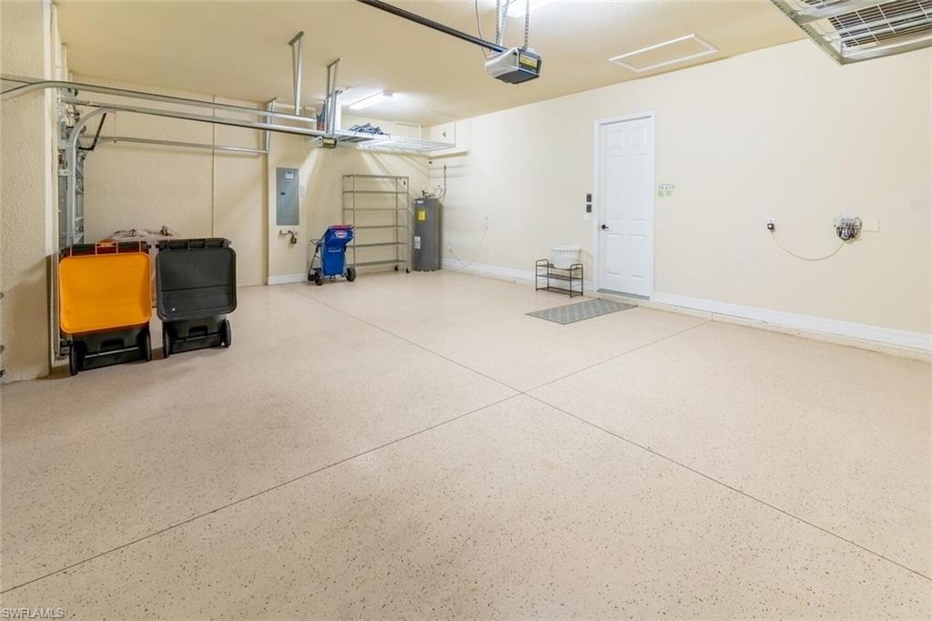 Garage with a garage door opener, water heater, and electric panel