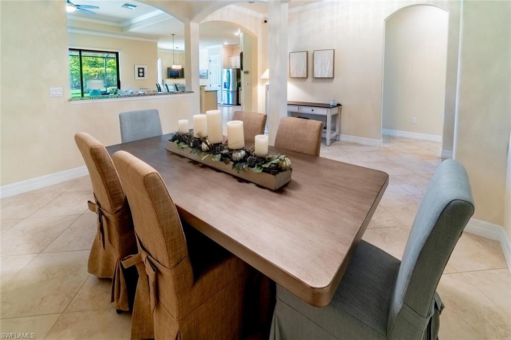 Tiled dining space with ceiling fan and ornamental molding