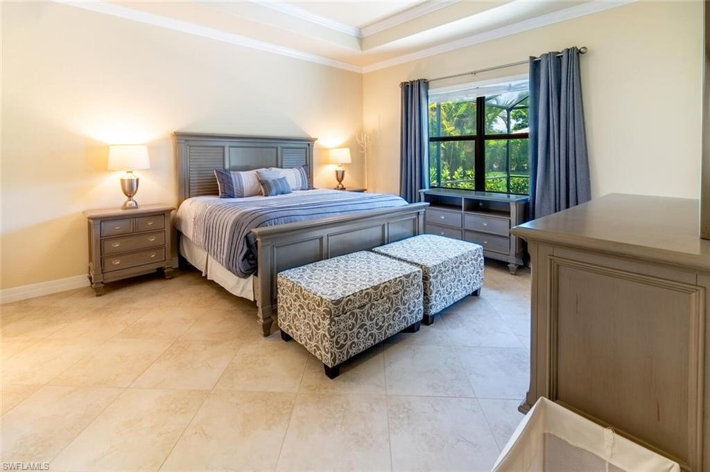 Tiled bedroom featuring a tray ceiling and ornamental molding