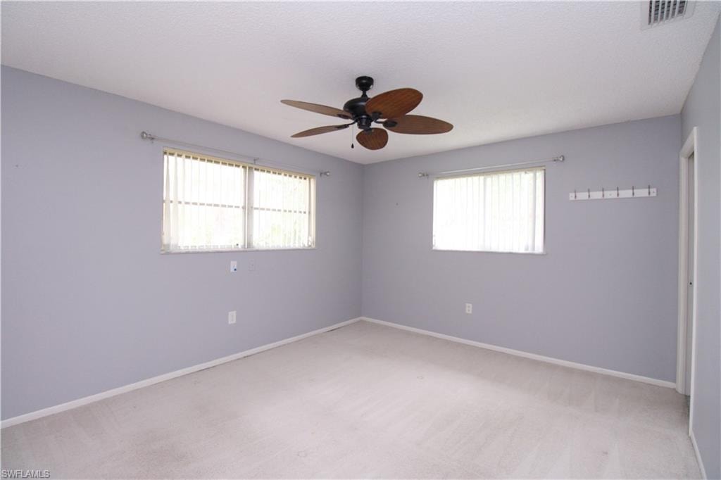 Unfurnished room with carpet, ceiling fan, and a healthy amount of sunlight
