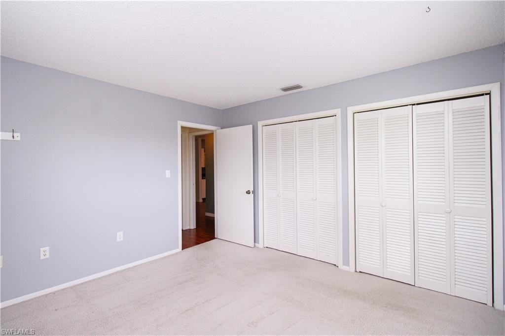 Unfurnished bedroom with multiple closets and carpet floors