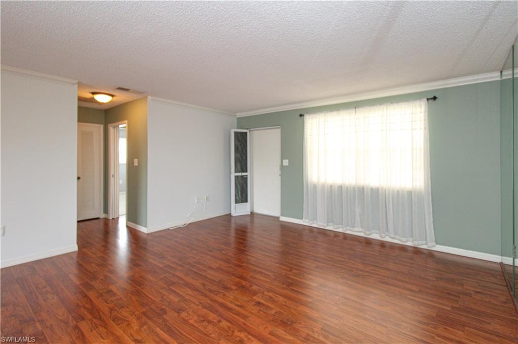 Unfurnished room featuring crown molding, dark hardwood / wood-style flooring, and a textured ceiling