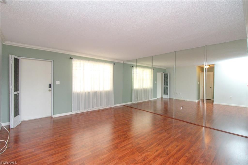 Unfurnished bedroom featuring a textured ceiling, ornamental molding, and wood-type flooring