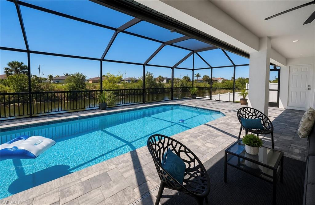Screened outdoor living area with a rectangular swimming pool, paver deck, and channel access