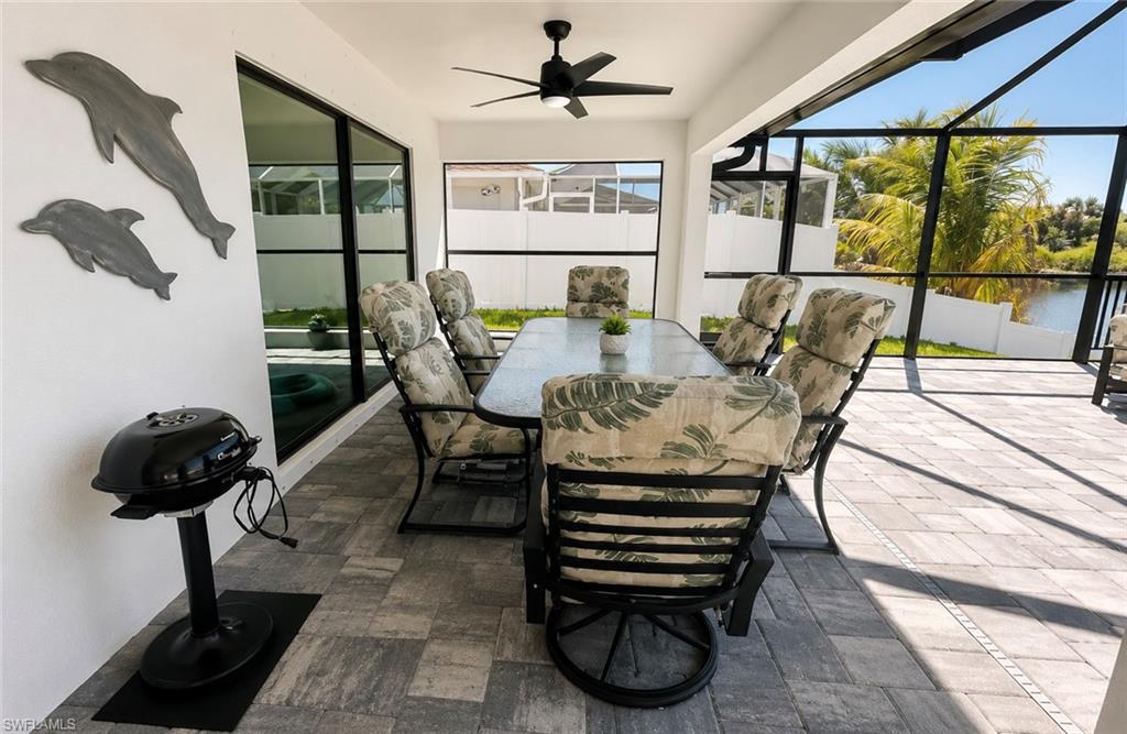 Screened lanai featuring paver flooring, black ceiling fan, and large windows