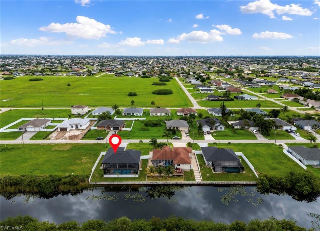 Waterfront property featuring a screened-in pool, white perimeter fencing, and a black roof