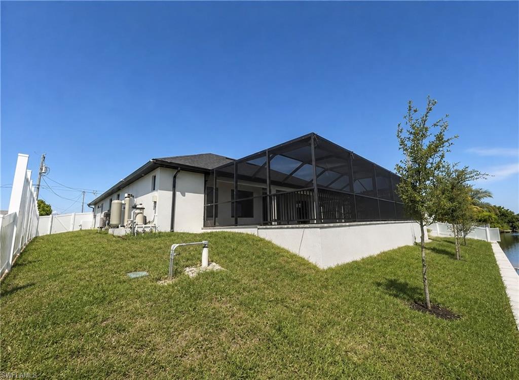 Screened lanai, white stucco exterior, black asphalt shingle roof, white vinyl privacy fence, waterside setting