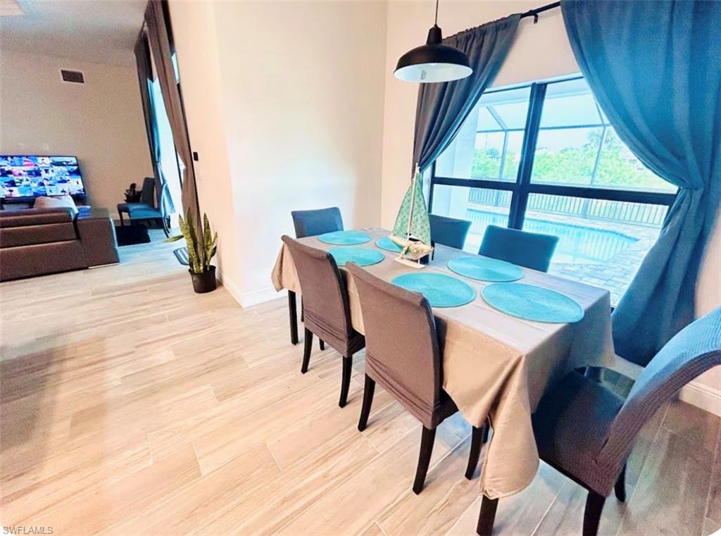 Wood-finish flooring throughout, with a dining area featuring a window overlooking a screened pool enclosure