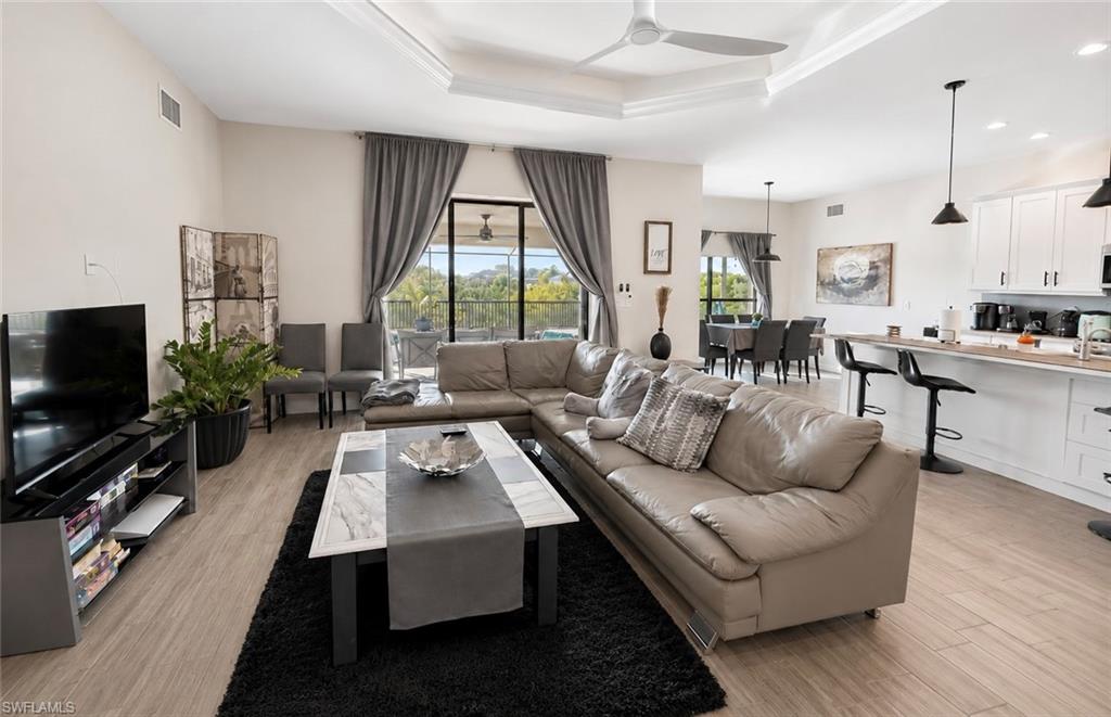 Open-concept living area featuring a neutral color palette, wood-finish flooring throughout, and expansive windows with natural light