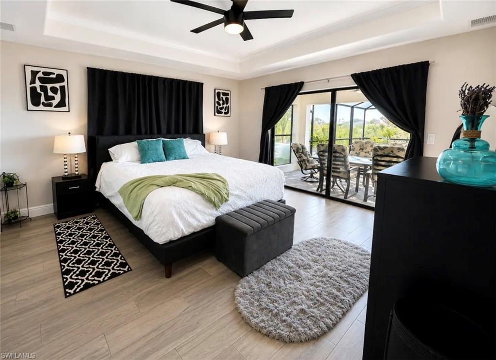 Spacious master bedroom featuring ceramic flooring, a tray ceiling, and a ceiling fan