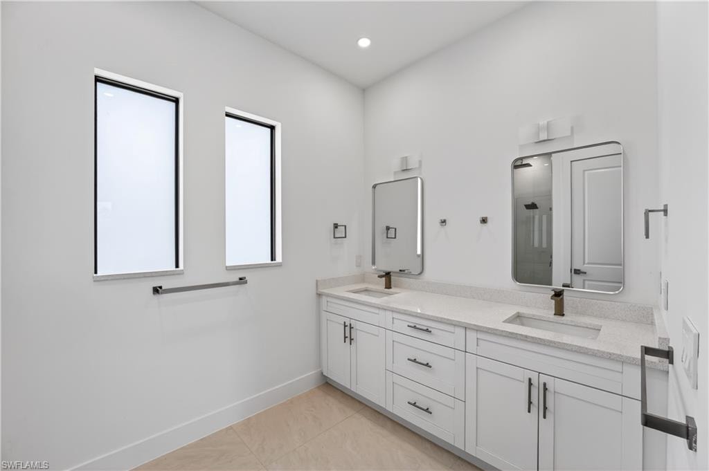 Dual vanity with white cabinetry, light-toned countertops, and bronze-finish fixtures