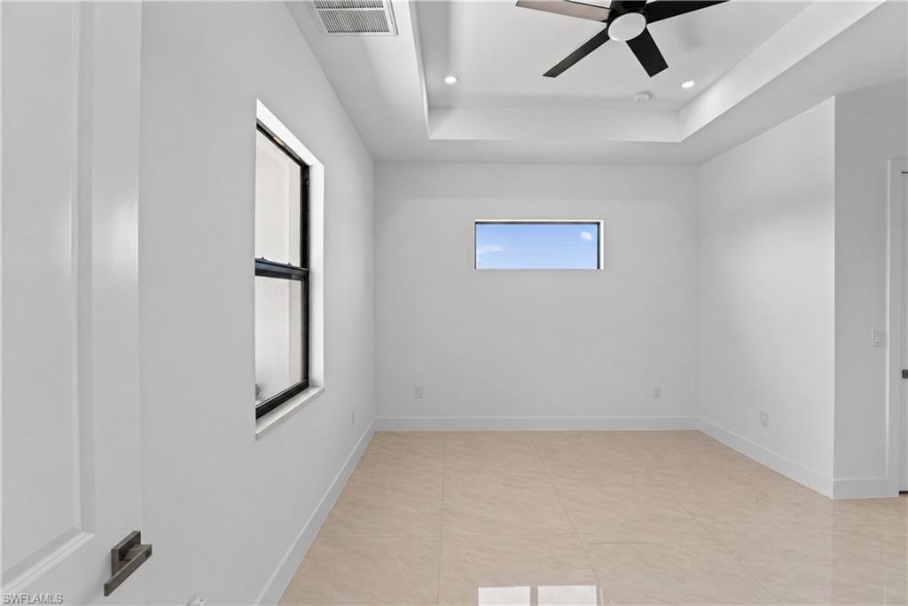 Spacious room featuring light-toned tile flooring, white walls, and a contemporary ceiling fan