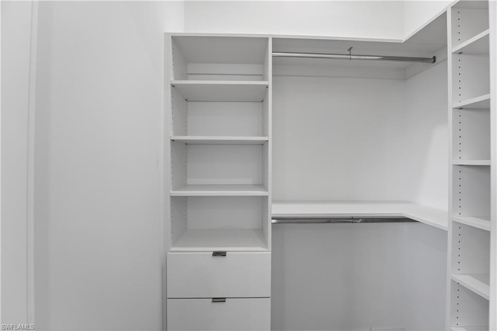 Custom closet system featuring white built-in shelving, two integrated drawers with modern pulls, and dual chrome hanging rods