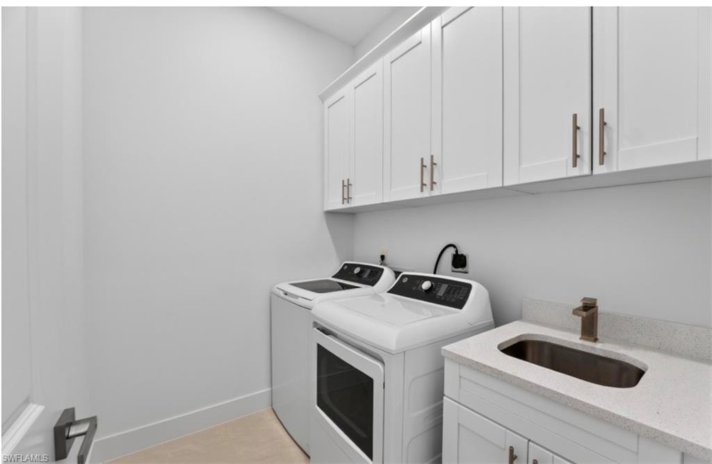 Dedicated laundry space featuring white shaker cabinetry with brushed bronze hardware, a utility sink with a bronze faucet, and a light-toned countertop