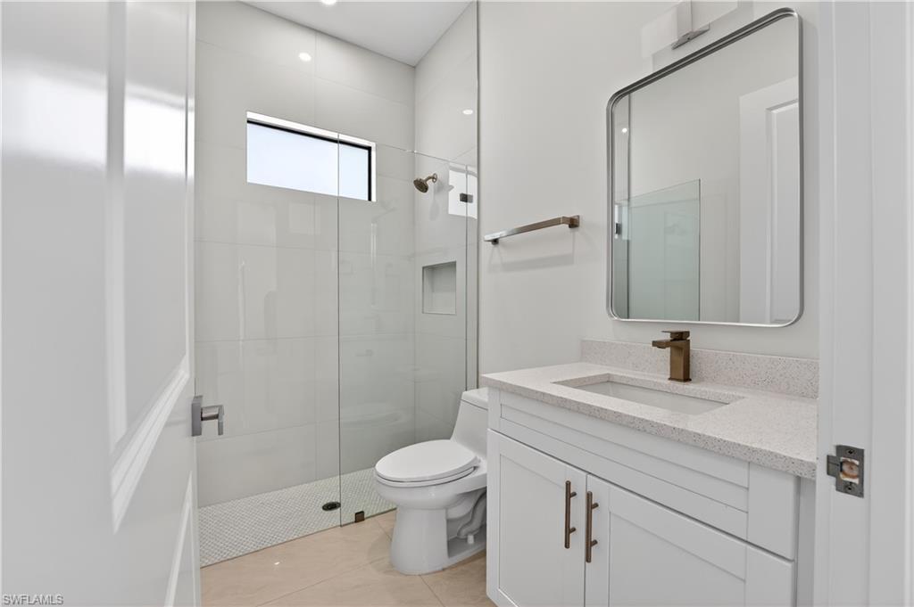 Modern bathroom featuring a glass-enclosed shower with tile surround, a built-in shower niche, and a transom window
