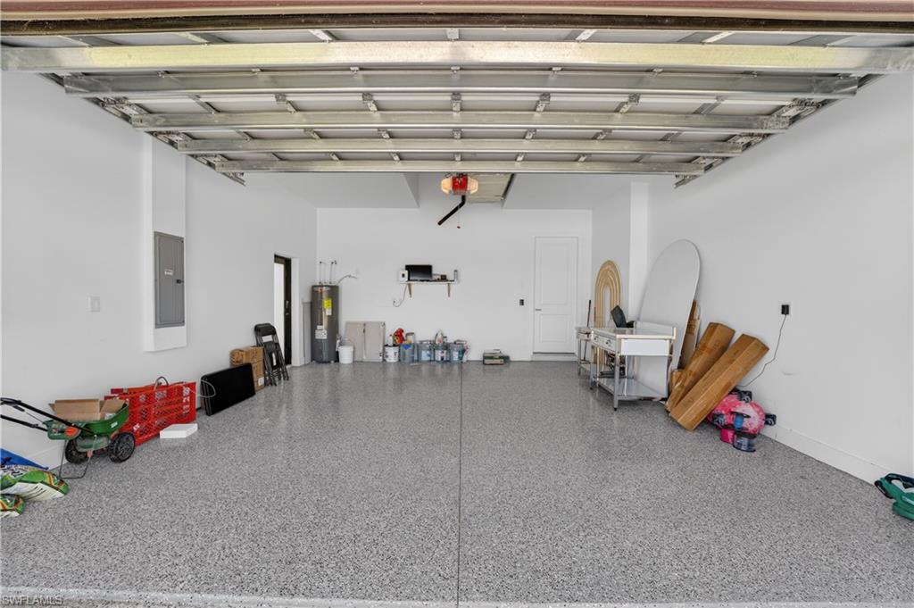 Spacious garage featuring a speckled epoxy floor, white painted walls, and a water heater