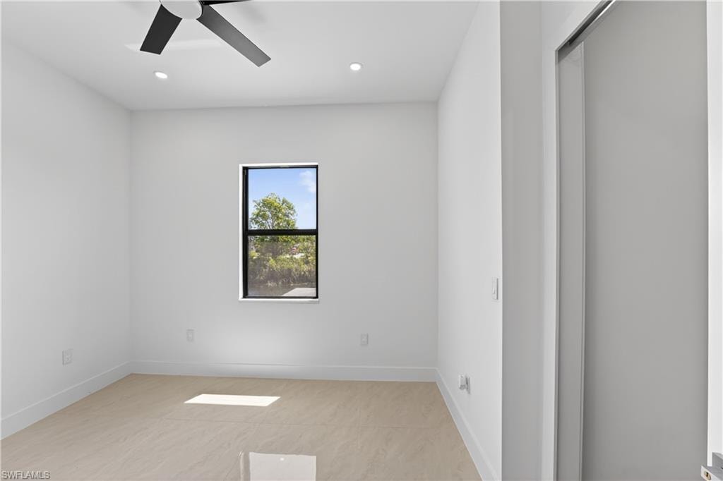 Bright interior space featuring a window with exterior tree scenery, a modern ceiling fan, recessed lighting, and tile flooring