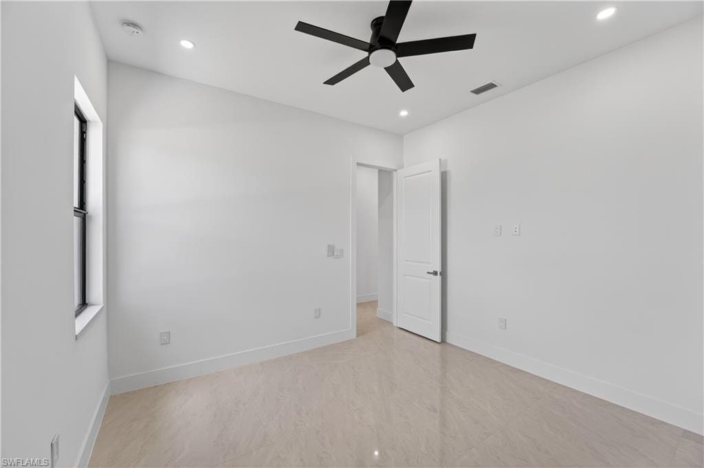 Contemporary interior space featuring light-toned large format tile flooring, a black ceiling fan, recessed lighting, and a white paneled door
