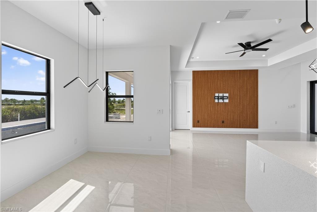 Open-concept living area featuring light-toned tile flooring and a decorative wood-panel accent wall