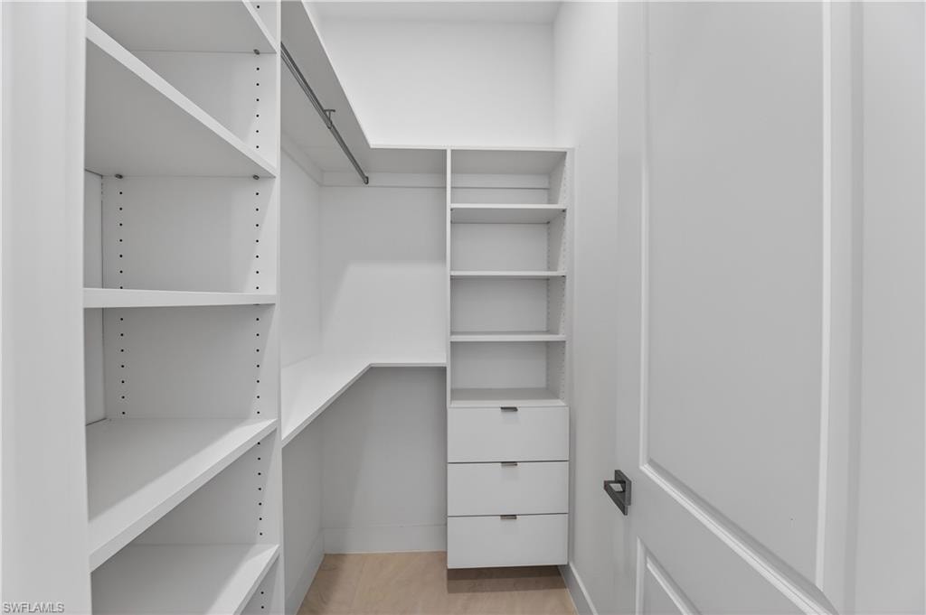 Walk-in closet with custom built-in shelving, hanging rods, and three integrated drawers