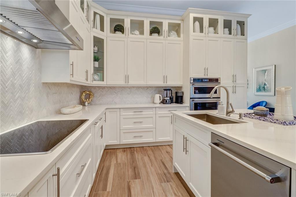 Kitchen featuring white cabinetry, sink, wall chimney range hood, and stainless steel appliances
